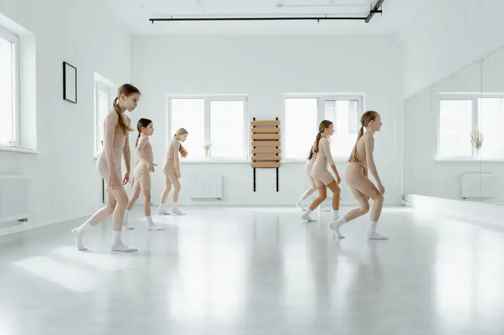 Students practicing arm movements in a bright dance studio